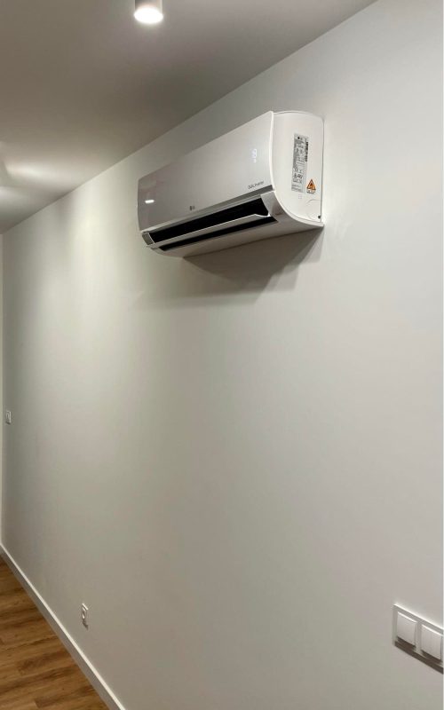 biała jednostka klimatyzacji na białej ścianie